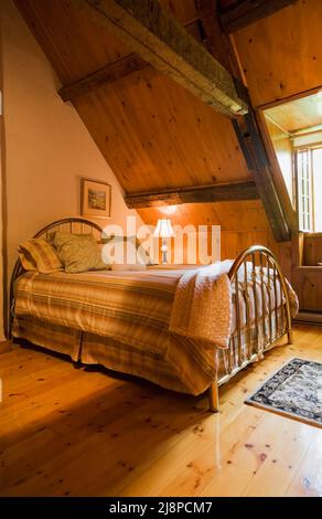 Brass bed in guest room on upstairs floor inside old circa 1740 Canadiana cottage style home. Stock Photo