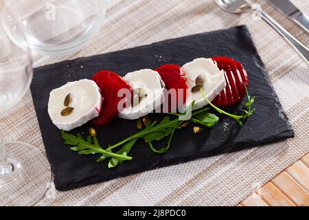 Slices of boiled beets with goat cheese, arugula and pumpkin seeds Stock Photo