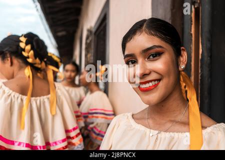 Pretty young latin woman smiling and looking at camera wearing folkloric dress from Nicaragua. Group of young friends Stock Photo