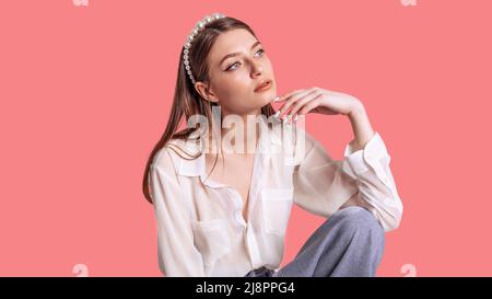 Portrait of a young lady on a pink studio background. Gorgeous blonde dreaming and waiting for a gift. Stock Photo