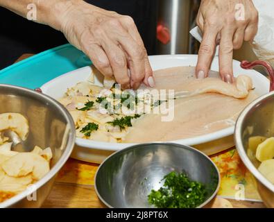 Chef lays out the fish fillet to prepare fish gratin with potatoes and apples. Exquisite French cuisine. Stock Photo