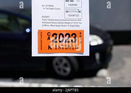 DMV California registration tag 2023 sticker, attached to renewal notice, close up next to blurred parked vehicle - San Jose, California, USA - 2022 Stock Photo