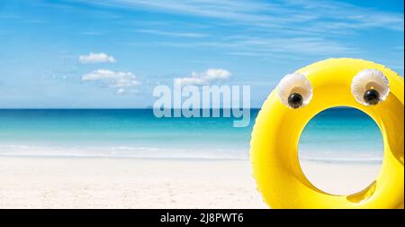 Large yellow rubber inflatable ring on sea side background at sunny day, tropical summer holiday concept Stock Photo