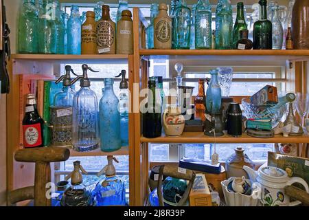 Assortment of old vintage glass bottles and containers on display on shelves in antique shop window, Uppingham, England, UK Stock Photo
