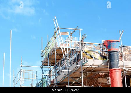 Scaffold installed around houses to provide access for bricklayers and other trades on construction site Stock Photo