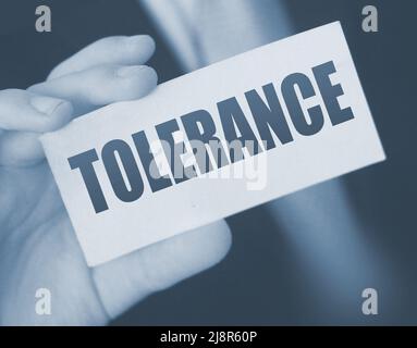 Tolerance words on a card in businessman hand. Social concept against discrimination at workplace. Stock Photo