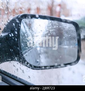 View of the rear view mirror on a rainy day from inside the car. Blurred view Stock Photo