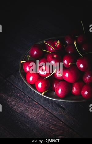 Dark red cherries on a pewter plate. Low light, upright composition. with copyspace Stock Photo