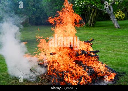 A garden bonfire with flames raging and smoke billowing out from the side Stock Photo