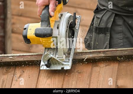 https://l450v.alamy.com/450v/2j8r9d4/cordless-dewalt-circular-saw-skilsaw-being-used-to-cut-through-old-wooden-fence-panels-2j8r9d4.jpg