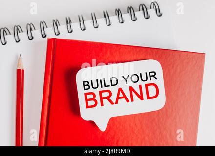 Text Build Your Brand on a white sticker with office stationery background. Flat lay on business, finance and development concept Stock Photo