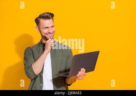Portrait of attractive minded cheerful guy hacker geek using laptop deciding order booking isolated over bright yellow color background Stock Photo
