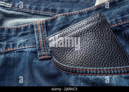 Black men's wallet in the front pocket of old shabby jeans Stock Photo