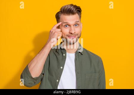 Portrait of attractive cheerful blond guy touching temple clue guess isolated over bright yellow color background Stock Photo