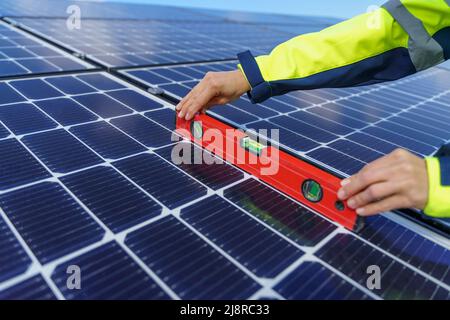 Close-up of woman engineer measuring solar photovoltaic panels on roof, alternative energy concept. Stock Photo