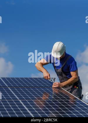 Man worker installing solar photovoltaic panels on roof, alternative energy concept. Stock Photo