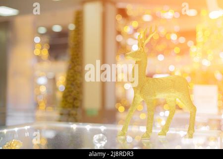 A golden glittering deer stands in bright Christmas sparkling interior. Soft focus. Stock Photo