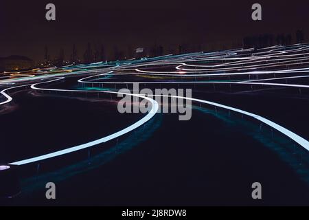 Large walking area with luminous winding lines at night. Unusual landscape design Stock Photo