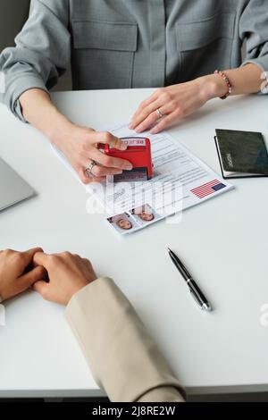 Vertical high angle view in unrecognizable US embassy worker putting rejected stamp on visa application after interview Stock Photo