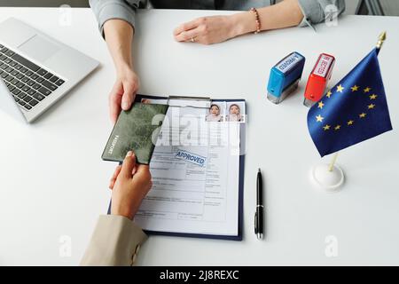 From above view shot of unrecognizable Muslim woman High angle of unrecognizable woman giving her passport to consular officer to make USA travel visa Stock Photo