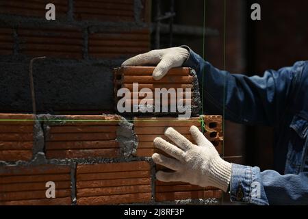 Close up of bricklayer installing bricks on construction site. Concept of repair and building materials Stock Photo