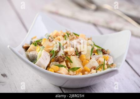 Chicken salad with pineapple, corn and cucumber dressed with Greek yogurt, crushed nuts and cheese. Stock Photo