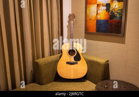 A Yamaha acoustic guitar on a sofa in a modern apartment living room. Stock Photo