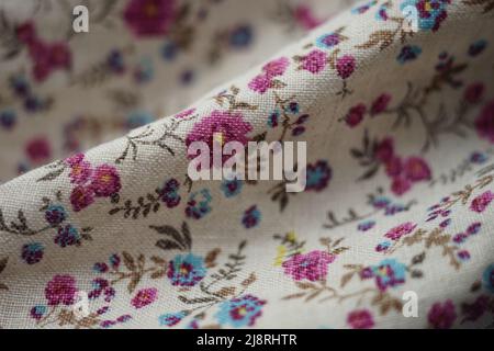 Linen fabric with a floral pattern, pink and blue flowers on a beige material. Stock Photo
