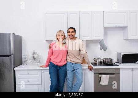 happy multiethnic couple standing in modern kitchen Stock Photo