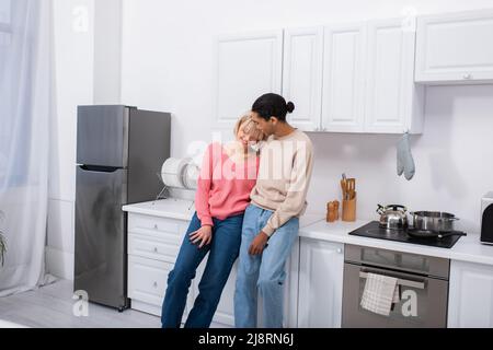 happy multiethnic couple hugging in modern kitchen Stock Photo