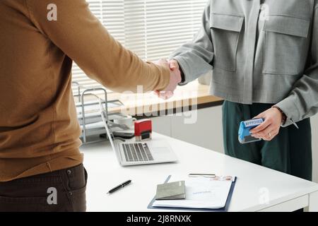 Unrecognisable woman working as consular officer shaking hands with man after successful interview and visa application approval Stock Photo