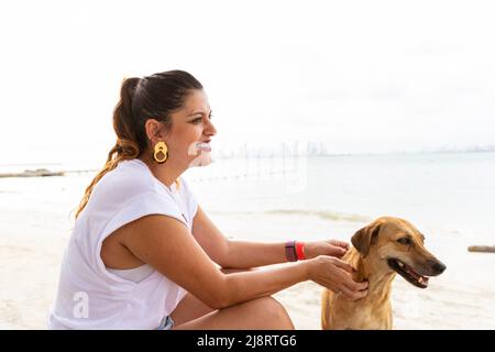 latina woman with her mongrel dog in a beach Stock Photo