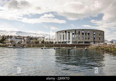 Akureyri, Iceland, April 29, 2022: the Hof cultural and conference center reflecting in the town's harbour Stock Photo