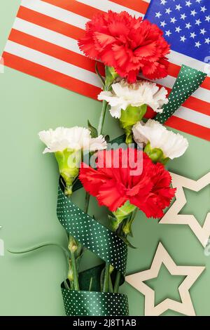 American holiday banner with bouquet of carnations, American flag and wooden stars on a green background. American holiday card suitable for Memorial Stock Photo