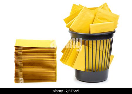 Yellow padded envelopes neatly stacked and randomly tossed into an office trash bin isolated on white background. Stock Photo