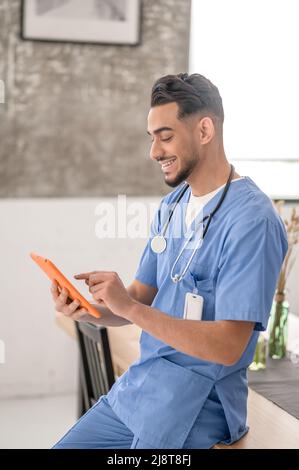Joyful Caucasian male physician using his gadget Stock Photo