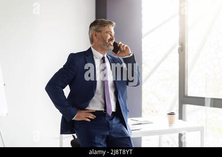 Business Call. Confident Middle Aged Businessman Talking On Cellphone At Office Stock Photo