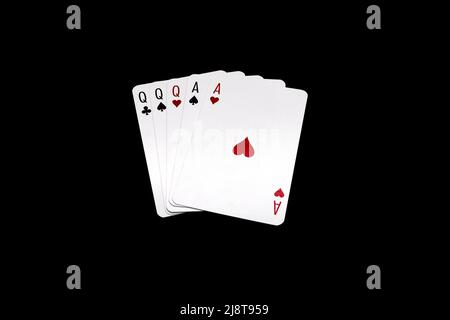 Full House of queens and aces.  Poker hand isolated on black background Stock Photo