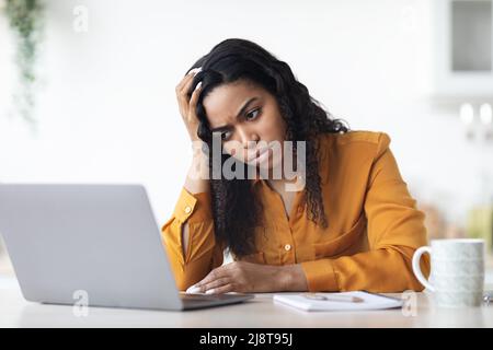 Upset black lady freelancer working on laptop at home Stock Photo