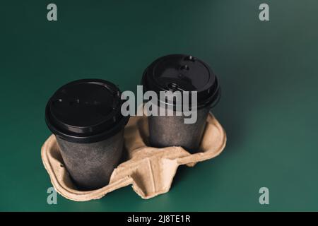 Disposable cups on stand against green background Stock Photo