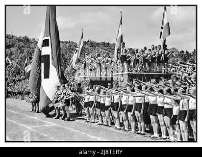 1930s Hitlerjugend Hitler Youth together with BDM The League of German Girls or the Band of German Maidens  Bund Deutscher Mädel, abbreviated as BDM  the girls' wing of the Nazi Party youth movement of the Hitler Youth. It was the only legal female youth organization in Nazi Germany. Together at a regional sports festival of  Hitler Youth and the BDM in Tübingen on the university sports field with Swastika flags and banners giving the Nazi salute Tubingen Nazi Germany 1937 Stock Photo