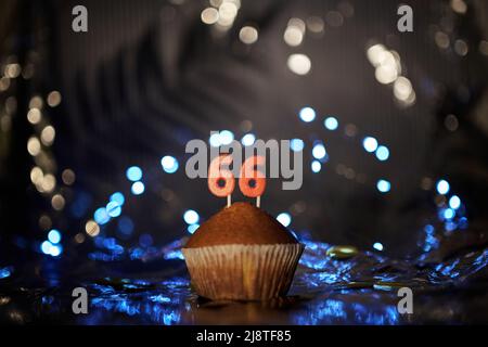 Tasty fresh homemade vanilla cupcake with number 66 sixty six on aluminium foil and blurred bright background in minimalistic style. Digital gift card birthday concept. High quality image Stock Photo