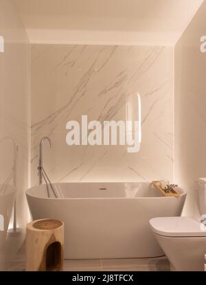 Beautiful luxury bathroom white and marble carrara with exempt bathtub and led as ambient light to relax with a minimalist design Stock Photo