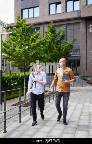 Real estate managers or financial business team talking outdoor modern building background. On the go meeting in downtown near office. Construction, architecture specialist concept. High quality image Stock Photo