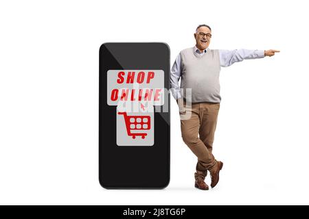 Mature man leaning on a big mobile phone with text shop online and pointing to the side isolated on white background Stock Photo