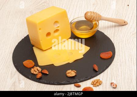 Different types of cheese on a graphite board with nuts and dried fruits Stock Photo