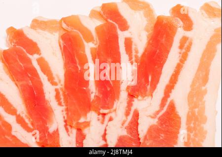 Several pieces of bacon cut into strips on a white background Stock Photo