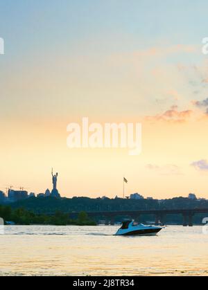 Sunset view of Mother Motherland monument, motor boat on Dnipro river, Paton bridge. Kiev, Ukraine Stock Photo