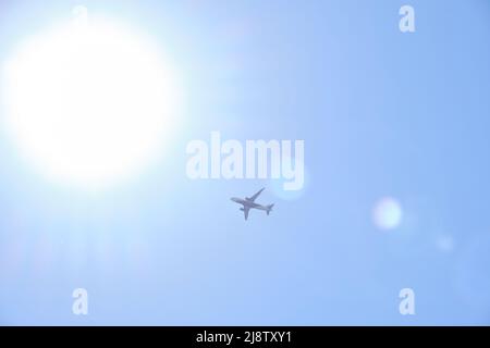 Plane taking against background of clear blue sky and bright sun Stock Photo