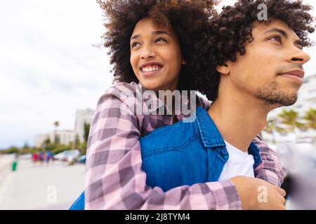 Young afro african american couple piggybacking while spending leisure time together Stock Photo